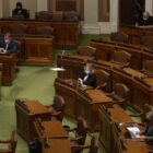 a few masked lawmakers sit socially distanced inside