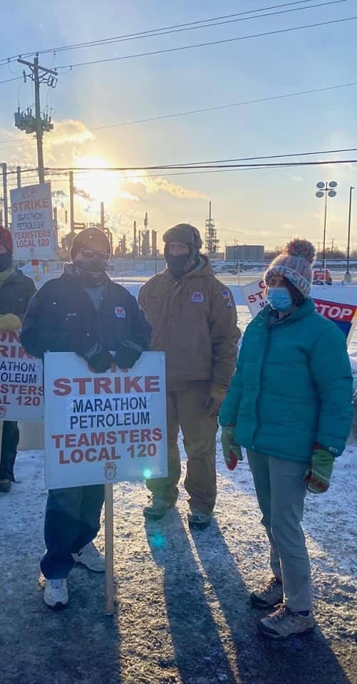 Amy Klobuchar next to 2 Marathon oil workers holding a sign