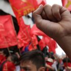 a close up of a fist held up in front of a blurry background of red flags