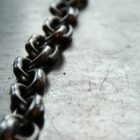 a line of steel chains lie on grey concrete ground